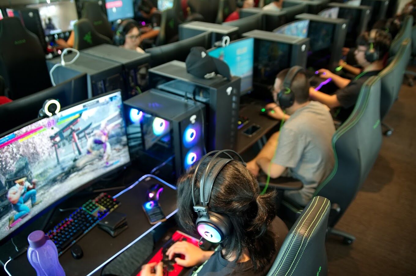 back view of woman wearing headphones gaming on pc computer in titan esports gaming